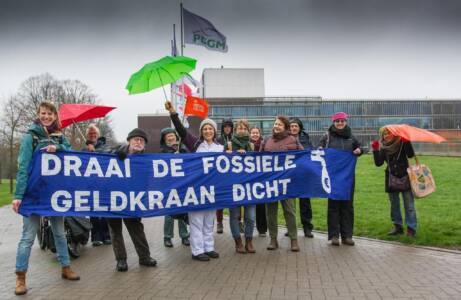 Vrolijke demonstranten dragen een spandoek: 'draai de fossiele geldkraan dicht'