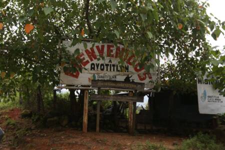 Bord tussen de bomen met de tekst 'Bienvenidos a Ayotitlán'